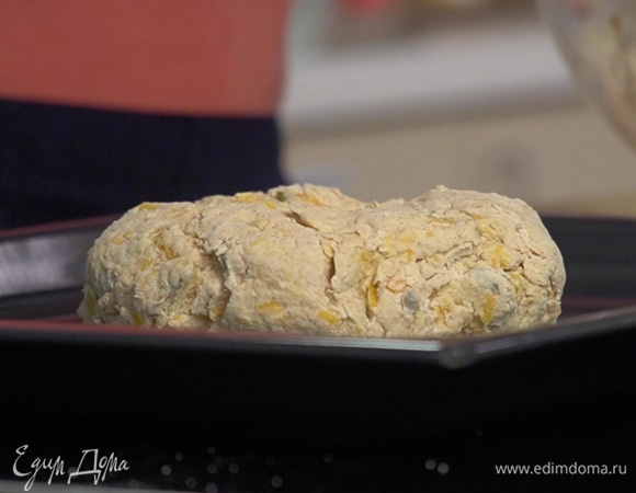 Сформировать из теста шар, выложить на противень и слегка прижать его руками, сверху сделать ножом крестообразный надрез.