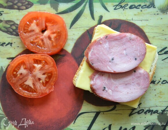 На поджаренную сторону целого куска хлеба выложите сыр, затем — колбасу.