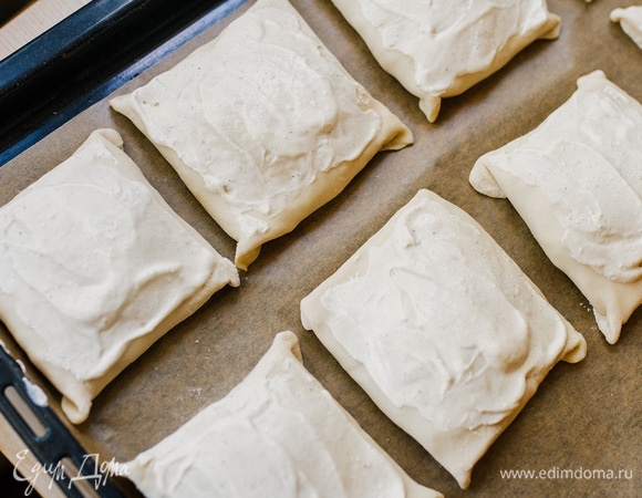 На противень положить пирожки швом вниз. Смазать оставшимся соусом и выпекать при 180°C 30–40 минут.