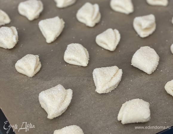 Обмакнуть одну сторону теста в сахар и сложить круг пополам, повторить то же самое с кусочком теста дважды. Заготовки выложить на застеленный пергаментом противень.