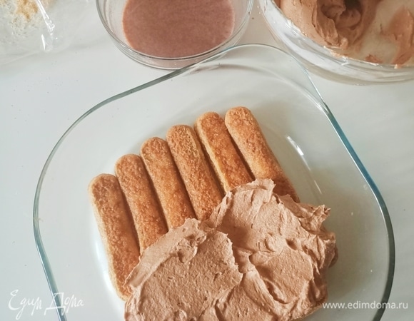 Далее берем форму, лучше прозрачную, тогда десерт будет выглядеть красивее. На дно укладываем печенье, предварительно окунув его в шоколадное молоко. Сверху покрываем печенье кремом.