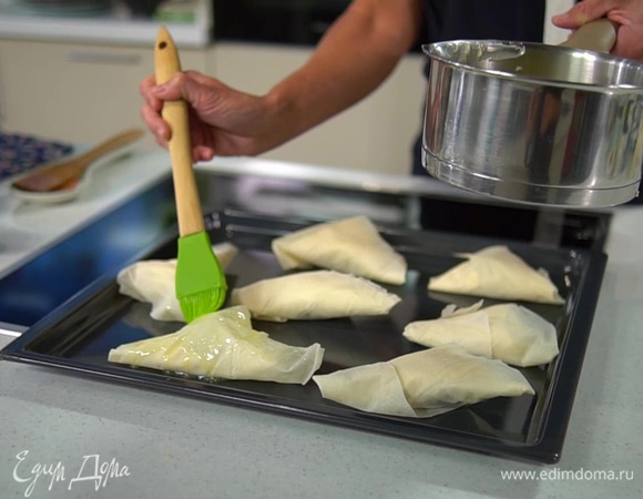 Выложить треугольники на противень, смазать растопленным маслом и выпекать в разогретой духовке 30 минут.