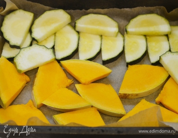 На противень постелите пергамент, выложите кабачки и тыкву.