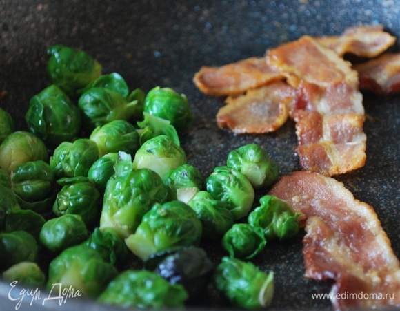 Брюссельскую капусту отварите в кипящей подсоленной воде в течение 1 минуты, откиньте на дуршлаг, чтобы стекла вода. Добавьте капусту в сковороду к бекону и прогрейте 2–3 минуты.