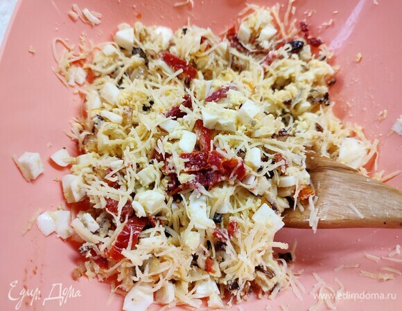 Для начинки яйца отварить и нарезать мелким кубиком. Лук обжарить на растительном масле до золотистого цвета. Вяленые помидоры нарезать полосками. Сыр натереть на мелкой терке. Все смешать, оставив 2 столовые ложки сыра для верха рулета.
