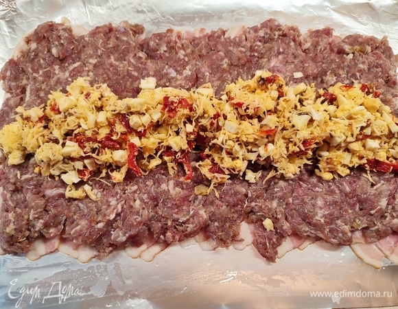 Поверх бекона выложить фарш, посередине положить начинку.