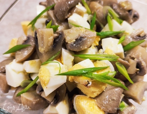 Яйца сварить вкрутую. Остудить, очистить и крупно нарезать. Добавить их к шампиньонам и перемешать. Дать постоять в холодильнике минут 20. Украсить зеленью. Можно подавать к столу.