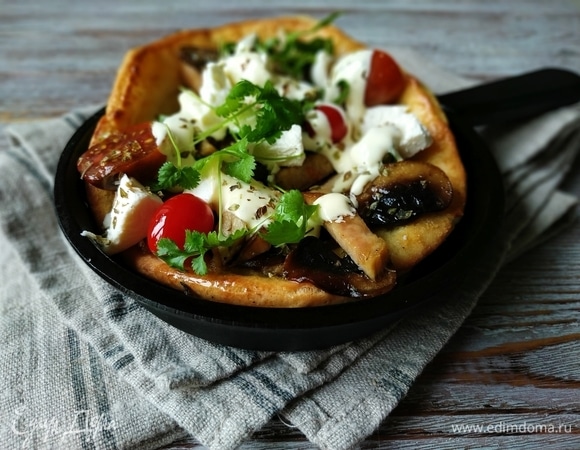 Сыр раскрошите руками, добавьте помидоры и зелень. Полейте блин с начинкой любимым соусом или сметаной. Подавайте сразу к столу.