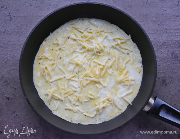 Сверху на яйца выкладываю половину натертого на терке сыра.