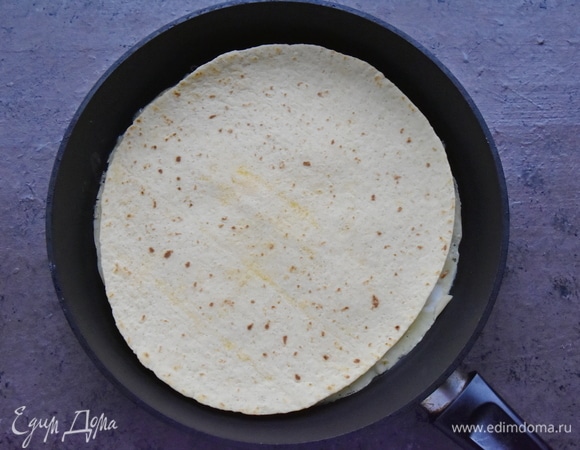 Затем накрываю первой лепешкой и дожидаюсь расплавления сыра. В этот момент можно накрыть сковороду крышкой на пару минут.