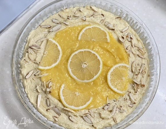Форму смазать маслом, припудрить мукой. Выложить тесто. Сверху и посередине — лимонный крем. На крем уложить тонкие ломтики лимона и посыпать миндалем. Выпекать около 40 минут при 180°C.