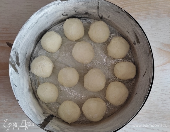 Форму для выпечки лучше выбрать силиконовую или разъемную. У меня форма диаметром 18 см. Форму смазать сливочным маслом и посыпать мукой, излишки муки стряхнуть. Из творожной массы сформировать шарики примерно по 4–5 см в диаметре и выложить в форму в произвольном порядке.
