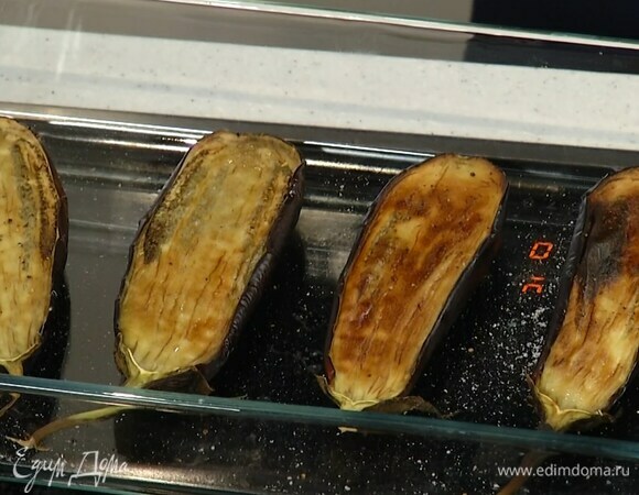 Баклажаны вместе с плодоножкой разрезать вдоль пополам, выложить срезами вверх в стеклянную форму, сбрызнуть 2 ст. ложками оливкового масла и запекать в разогретой духовке 15–20 минут.