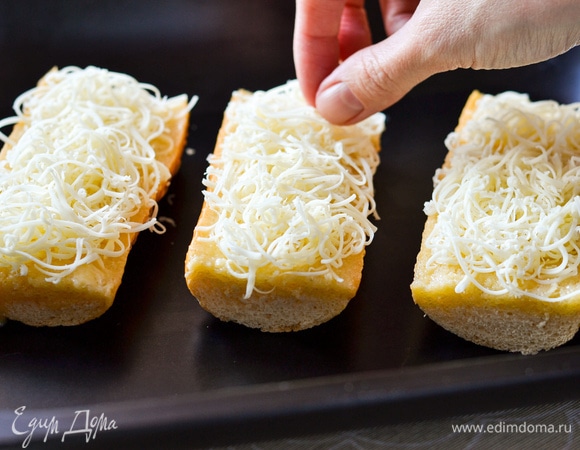 Сыр натереть на мелкой терке, распределить почти весь сыр по багету.