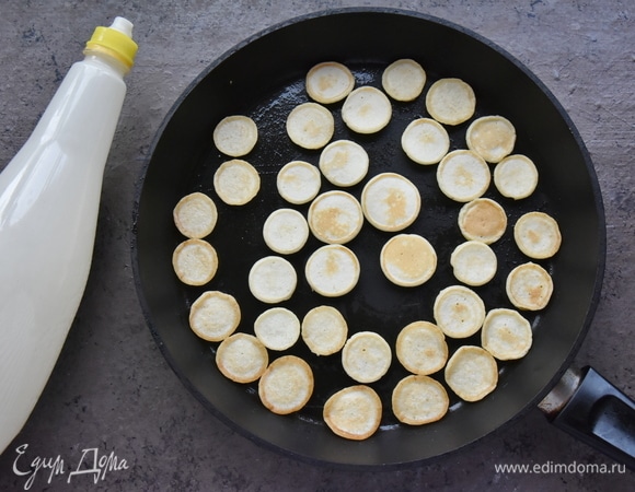 Сковороду разогреваю и смазываю растительным маслом. Для удобства можно перелить тесто в бутылку и использовать крышку с носиком. Можно выложить тесто на сковороду чайной ложкой. Размер оладий зависит только от вашего терпения. Поджариваю оладьи до подрумянивания с обеих сторон. Перекладываю готовые мини-блинчики в миску. Перед подачей дополняю ягодами, медом или сиропом.