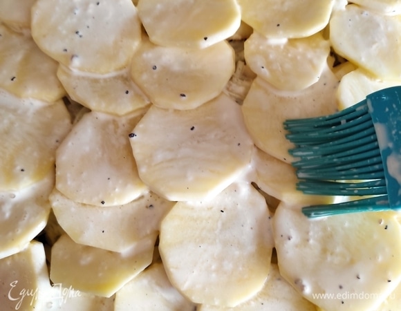 Сметану смешать с водой и кисточкой хорошо смазать картофельный слой, если смесь осталась, аккуратно вылейте ее сверху.