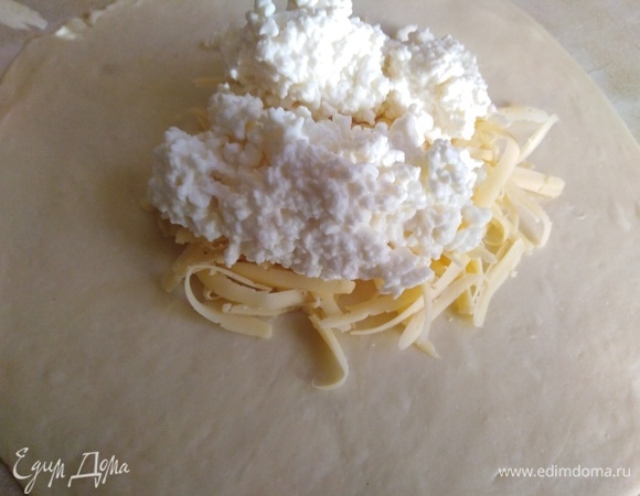 Каждую часть теста раскатать в тонкую лепешку. Выложить щепотку сыра, сверху — творог.