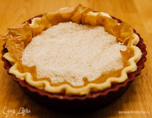 В форму положить лист пергамента и насыпать груз (рис или фасоль). Выпекать при 220°C 20 минут, затем убрать груз и выпекать еще 5 минут. Затем немного остудить основу.