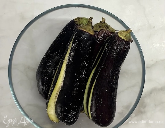 Хорошо посыпаем солью внутри и снаружи. Перекладываем в миску и оставляем на 20–30 минут. Баклажаны дадут сок, и горечь уйдет.