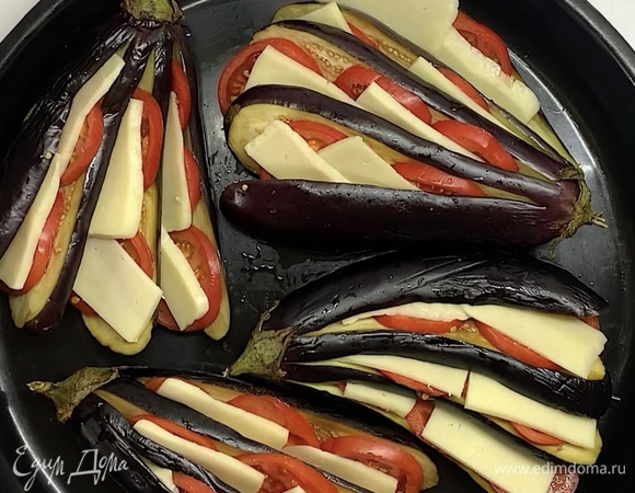 После промываем баклажаны и выкладываем веером в форму для запекания. Помидоры и сыр нарезаем на тонкие слайсы и вкладываем на баклажаны.