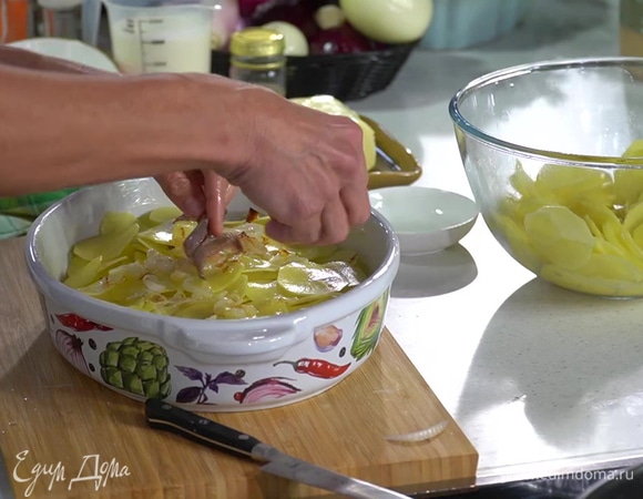 Картофель, слив воду, просушить бумажным полотенцем и выложить треть ломтиков тонким слоем в форму, сверху уложить слой анчоусов и лука, затем снова слой картофеля, слой анчоусов и лука, последним разложить слой оставшегося картофеля.