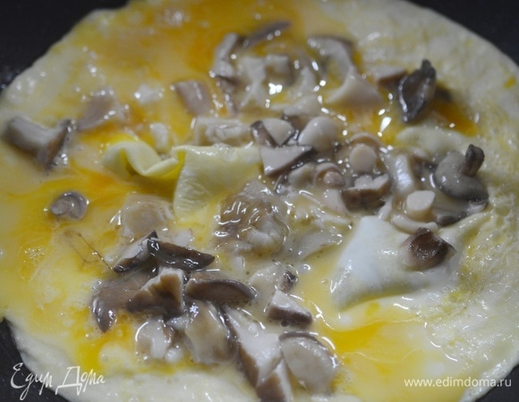 Как только омлет хорошо схватится по краям, выложите маслята.