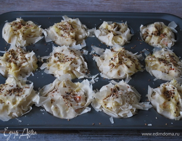 Начинку прикройте тестом, смажьте яйцом, посыпьте кунжутом. Выпекайте в духовке при температуре 170°C 35 минут. Следите, чтобы тесто фило не пригорело.