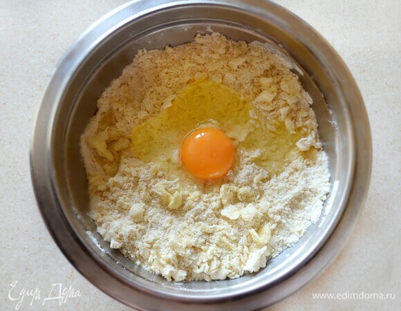 Готовим песочное тесто. Для этого в миску просейте муку, смешайте с сахаром и солью. Добавьте нарезанное кубиками холодное сливочное масло. Пальцами быстро перетрите муку с маслом до образования крупинок. Добавьте яйцо и быстро вымесите тесто. Сформируйте шар, оберните пищевой пленкой и уберите на 30 минут в холодильник.