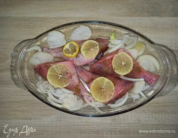 Почистить окуня, нарезать лимон. Противень смазать маслом, выложить рыбу, сделать на ней надрезы, посолить и поперчить. Сверху уложить лимоны. В свободное пространство выложить нарезанный лук. Отправить в духовку на 30 минут при 180°C.