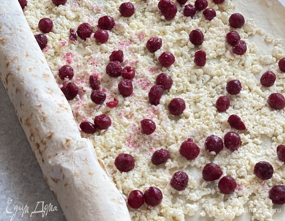 Творог смешать с яйцом и сахаром. Распределить равномерно по поверхности лаваша. Сверху разложить вишню без косточек. Можно использовать замороженную.