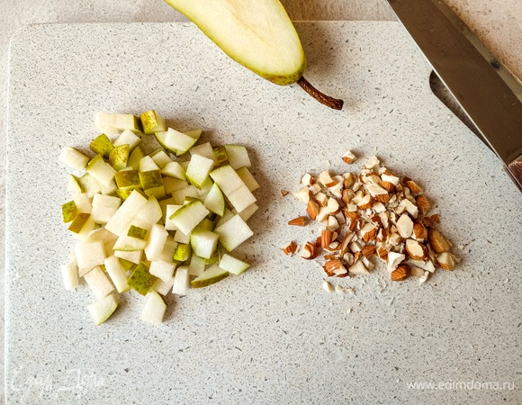 Спелую грушу нарезать кубиком. Орехи порубить.