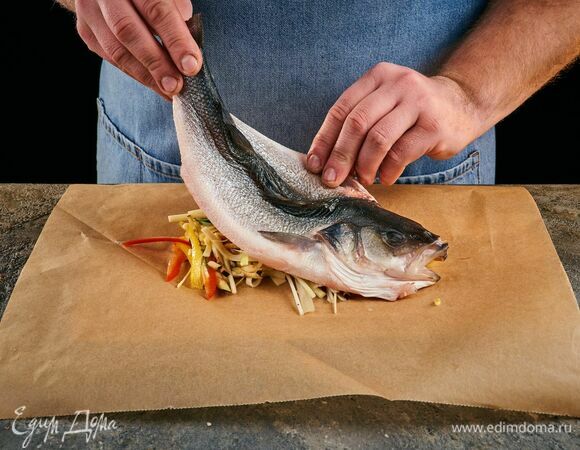 На два разных листа пергамента выложите овощи, а сверху положите очищенного сибаса.