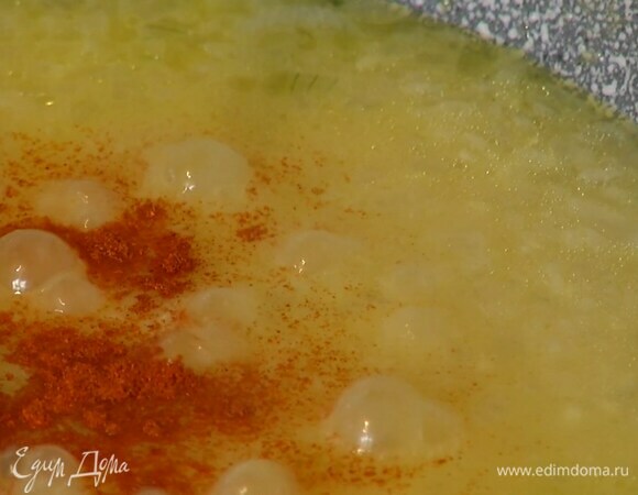 Влить к рису 2 половника горячего бульона, всыпать куркуму, паприку и прогревать, помешивая и вливая по мере выкипания оставшийся бульон.