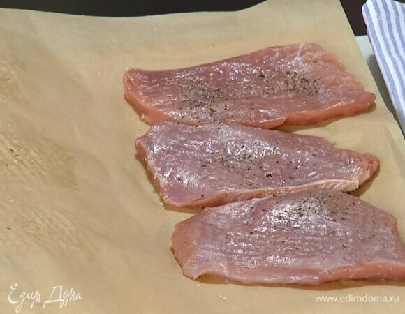 Индейку слегка посолить и поперчить, затем поместить между двумя слоями бумаги для выпечки и отбить.