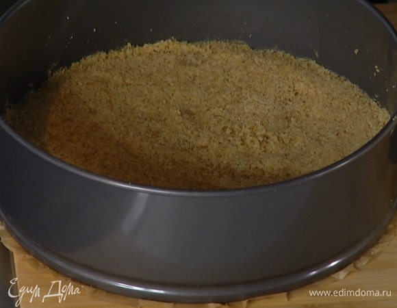 Дно разъемной формы застелить бумагой для выпечки, выложить измельченное печенье и плотно утрамбовать, так чтобы получился корж, затем отправить в холодильник.