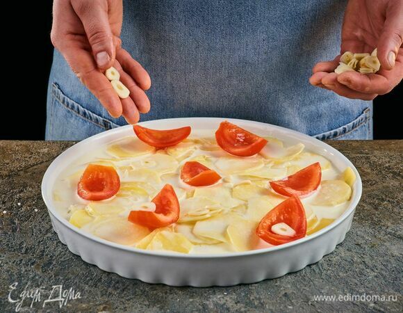 Сверху на картофель выложите помидоры и чеснок.