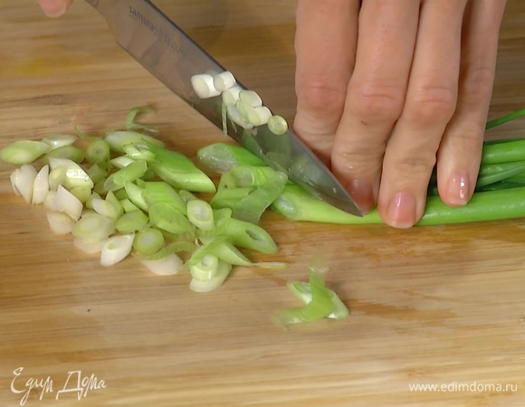 Зеленый лук нарезать, выложить к чесноку, добавить креветки и все обжарить.