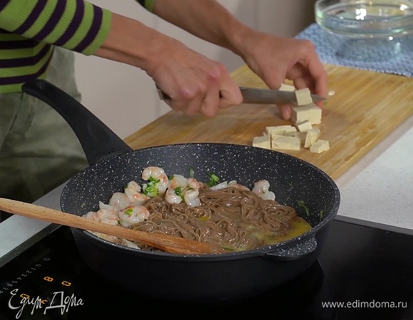 Тофу нарезать кубиками, выложить в сковороду с лапшой и перемешать, затем добавить ростки сои, влить рыбный и соевый соус.
