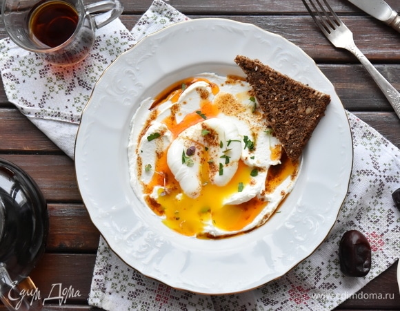 Осталось собрать воедино чылбыр. В тарелку выкладываю йогуртовую массу с чесноком, в центр помещаю яйцо пашот, немного рубленой зелени и поливаю ароматизированным маслом. Завтрак по- турецки готов!