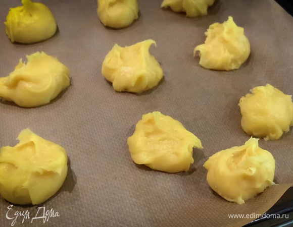 Противень застелить бумагой для выпечки и выкладывать смоченной в воде столовой ложкой шарики из теста с небольшим отступом друг от друга.