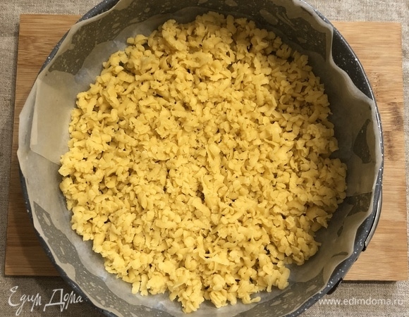 Достаем из холодильника тесто (2/3 части), натираем на крупной терке в форму для выпечки, распределяем вилкой, не придавливая. Отправляем в разогретую до 180°C духовку на 10 минут.