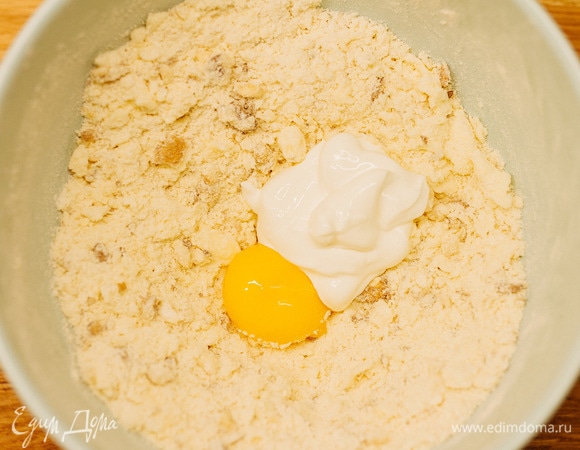 Сделать углубление, добавить желток и сметану. Замесить однородное тесто.