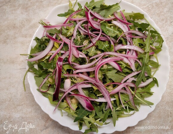 На тарелку выложить руколу и маринованный лук. Полить половиной заправки.