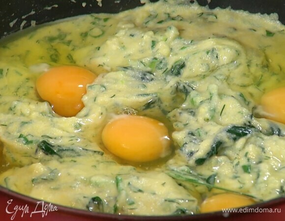 Нарубленную зелень и пармезан добавить в сковороду и все перемешать, затем сделать в поленте небольшие углубления и разбить в них яйца.