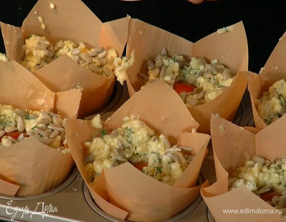 Разложить тесто в формочки с бумажными вкладышами, в каждую поместить помидор, слегка вдавить его и посыпать семечками.