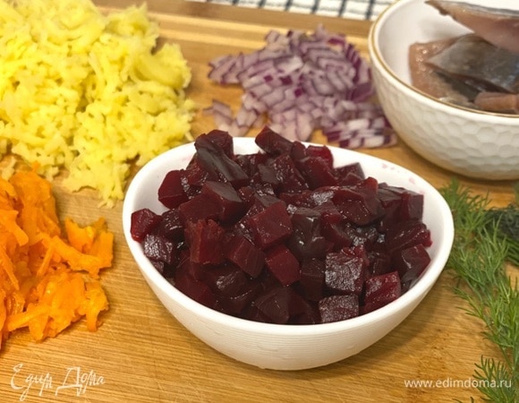 Подготовьте ингредиенты для салата: отварите и измельчите на терке морковь и картофель. Свеклу нарежьте кубиком, так она даст меньше сока. Сельдь и красный лук также нарежьте средним кубиком.