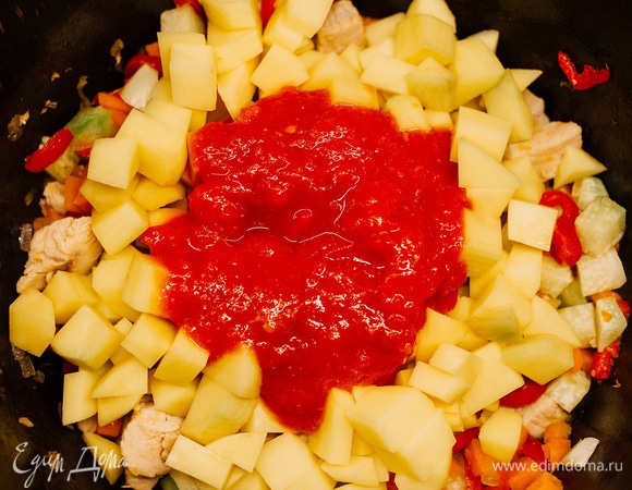 Добавить нарезанный кубиками картофель. Помидор залить кипятком, очистить от кожицы и пробить блендером, добавить к овощам в казан.