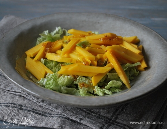 Салат выложите на тарелку, полейте заправкой. Сверху разложите манго.