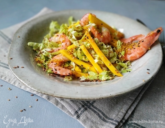 Перемешайте листья салата с манго, посолите по вкусу. Сверху разложите креветки, полейте заправкой и посыпьте обжаренными семенами кунжута. Подавайте к столу. Приятного аппетита.