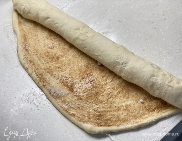 Раскатать тесто в пласт толщиной 0,5 см. Сливочное масло растопить, смешать с сахаром и корицей. Равномерно смазать раскатанное тесто. Свернуть в рулет.